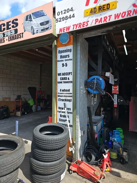 New tyres stacked at the Tyre Bay Bolton bay entrance, next to the opening hours board: Monday to Saturday 9 to 5 (photo shared by a customer on Google)